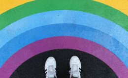 Photo of person standing in front of rainbow painted on street