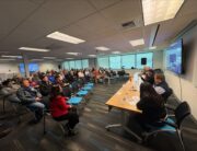 Photo of attendees sitting in chairs as panel speaks about the Harborview Bond Program