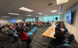 Photo of attendees sitting in chairs as panel speaks about the Harborview Bond Program